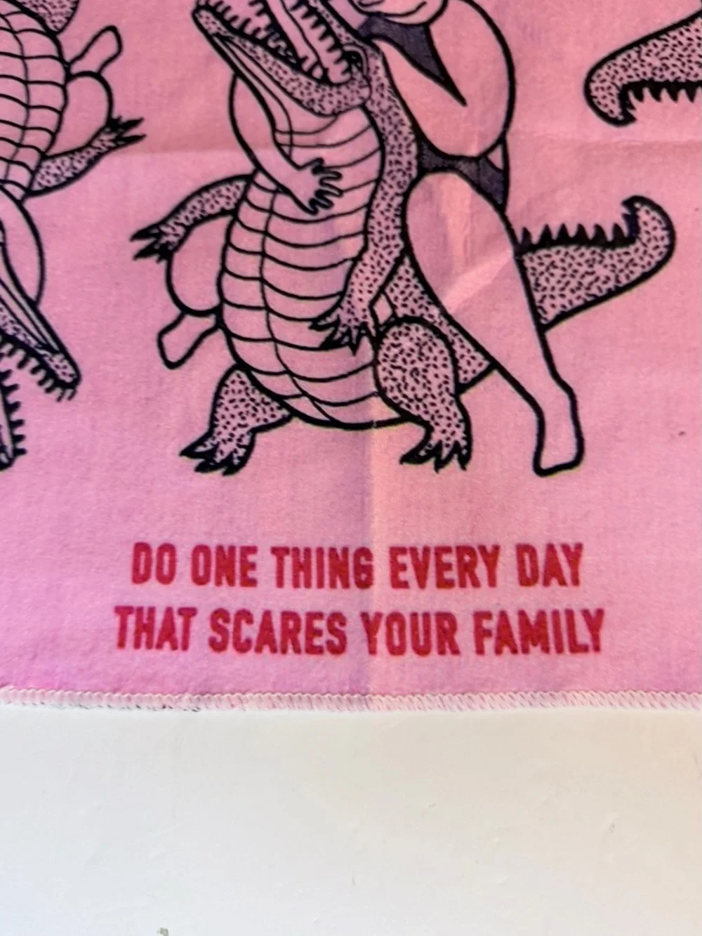 Funny pink dish / tea towel with a repeating print of a person wrestling an alli